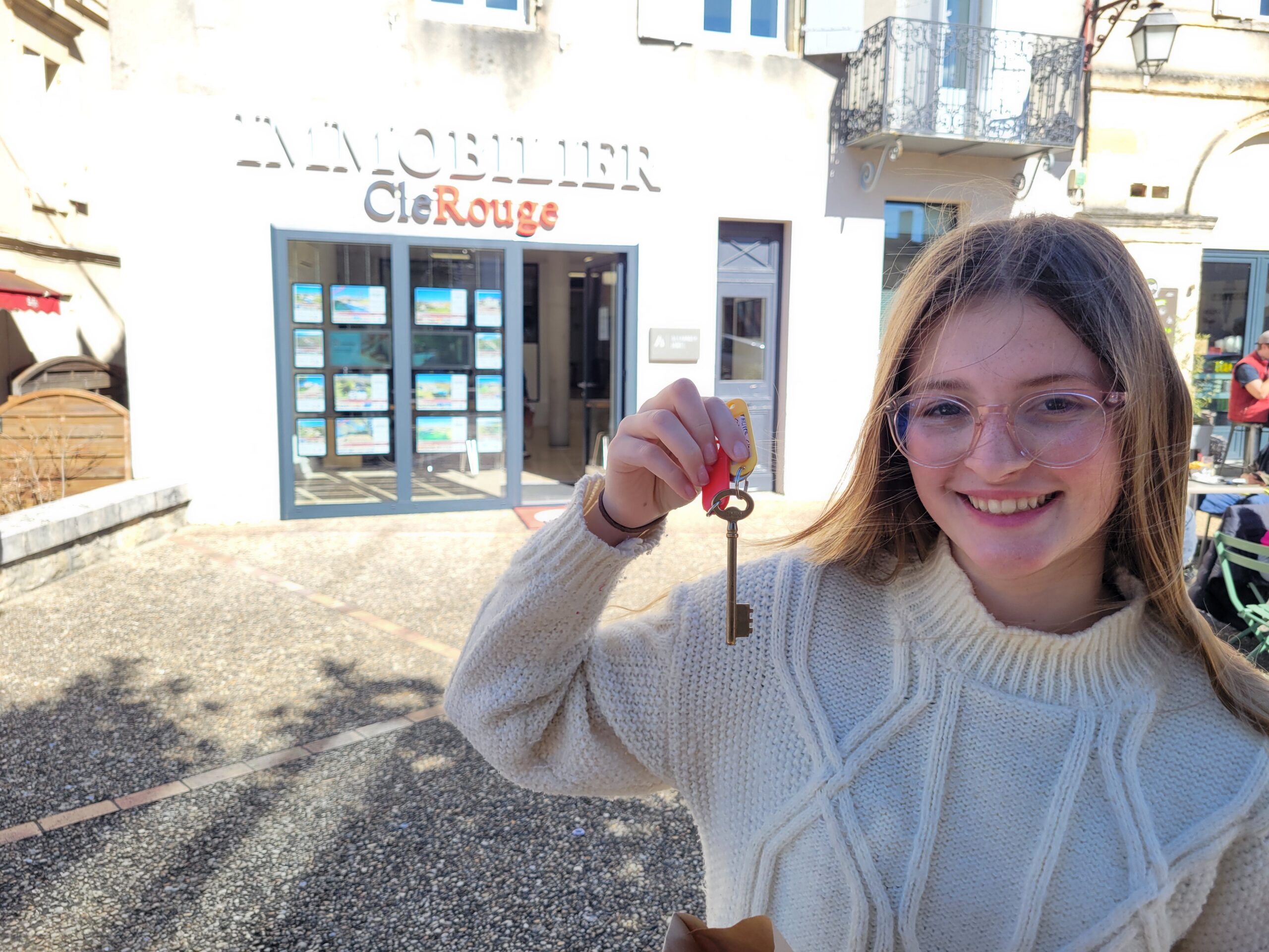 Adolescent girl holding skeleton key in front of real estate agency
